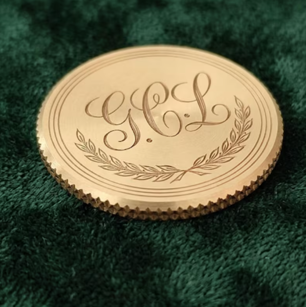 Brass golf ball marker laser engraved with an interlocking script monogram