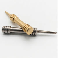 Brass and stainless steel barbell divot tools crossed, showing grooved grip rings and tapered single prong